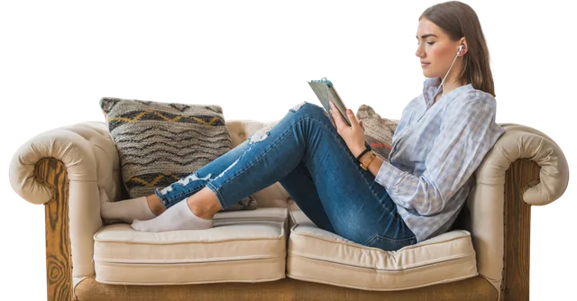 Eine Frau liegt mit Kopfhörern auf einem Sofa und liest auf einem Tablet
